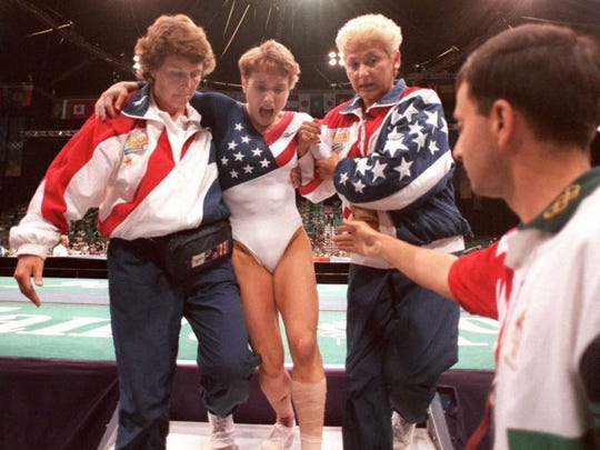 Trainer Martha Karoli (second from right) and doctor Larry Nassar help the injured Kerry off the platform.